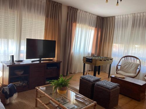 een woonkamer met een flatscreen-tv en een tafel bij Casa a 2 minutos andando a la playa de Panxón in Nigrán