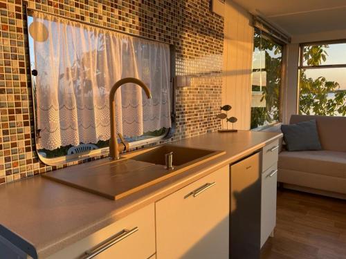 a kitchen with a sink and a window with a couch at Lawendowa Przystań WICKO 3 km od Międzyzdrojów in Międzyzdroje