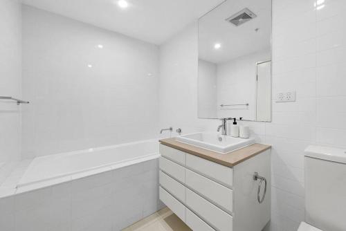 a white bathroom with a sink and a bath tub at The Fijian Hospitality in Brisbane