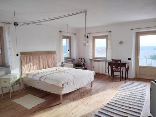 1 dormitorio con cama, mesa y ventanas en Riviera delle Langhe Wine Country House with a Pool, en Monchiero