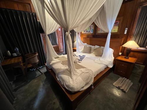 a bedroom with a bed with white mosquito netting at Japa Guesthouse in Canggu