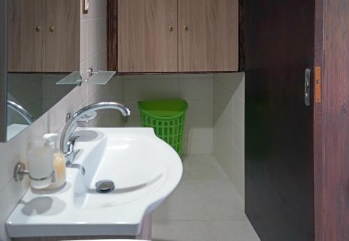 a bathroom with a white sink and a green basket at VENI Olive House in Kalamata
