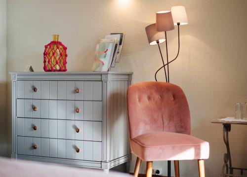 a bedroom with a chair and a dresser and a lamp at Landhotel Lindenhof in Feld am See