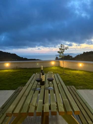 a wooden picnic table with two bottles of wine on it at Villa Long View in Avliótai