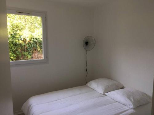 a white bedroom with a bed and a window at T3 en duplex avec grande piscine in Anglet