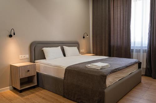 a bedroom with a large bed with a night stand at BnB Hotel Shymkent in Shymkent