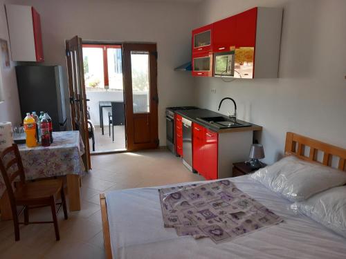 a bedroom with a bed and a kitchen with red cabinets at Apartments Zmaj in Zavala
