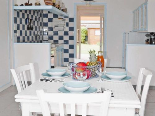 une table blanche avec un bol de fruits dessus dans l'établissement Maison 3 étoiles avec jardin clos, à 800 m de la plage, proche port de Saint-Sauveur, Île-Grande - FR-1-542-22, à Kerjagu