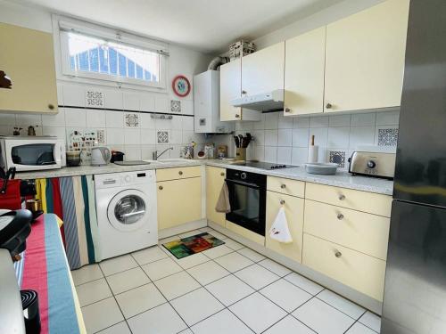 une cuisine avec des armoires blanches et une laveuse et une sécheuse dans l'établissement ARCACHON - Appartement 3 pièces avec terrasses et parking à 300m de la plage - FR-1-433-53, à Arcachon