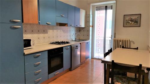 cocina con armarios azules, mesa y fogones en SPAZIOSO APPARTAMENTO, en Sondrio