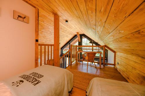 Habitación con cama y techo de madera. en Kaszuby - Komfortowe domki nad jeziorem en Barkocin