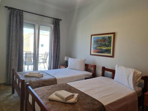 a hotel room with two beds and a balcony at Apollo Pavilion Apartments in Mirina