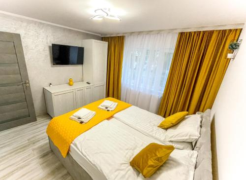 1 dormitorio con 1 cama con manta amarilla en Loghin Residence, en Suceava