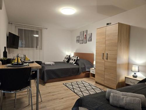 a bedroom with two beds and a desk and a cabinet at Holiness Apartmanok in Szeged