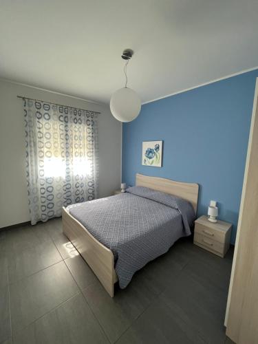 um quarto com uma cama e uma parede azul em Villetta Azzurra em Alcamo Marina