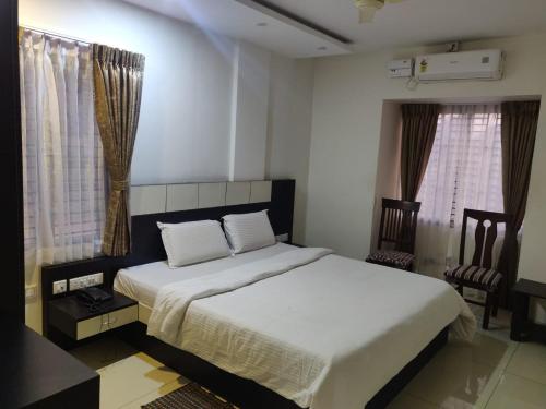 a bedroom with a white bed and two windows at SDK RESIDENCY in Shravanabelagola