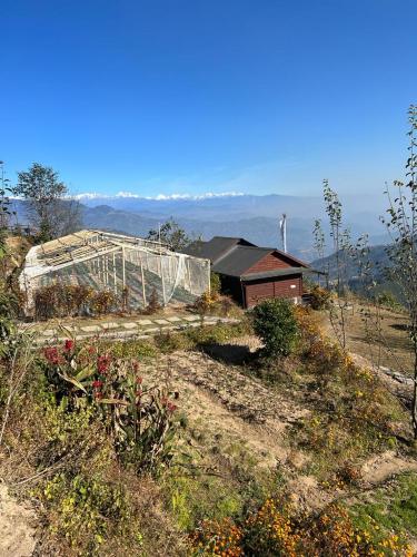 a greenhouse on the side of a hill with a house at Prakriti Resort and Organic Farm Pvt. Ltd. in Burhānilkantha