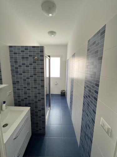 baño con lavabo blanco y suelo de baldosa azul en Villetta Azzurra, en Alcamo Marina