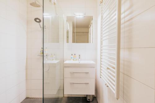 a white bathroom with a sink and a shower at Grand Hotel Opduin in De Koog