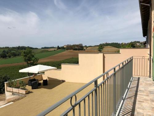 einen Balkon mit einem Tisch und einem Sonnenschirm in der Unterkunft Ca' dal Bertu - Cascina in Monferrato in Rosignano Monferrato