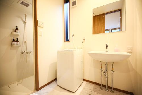 a white bathroom with a sink and a shower at PrimeRoom別府 浜脇 in Beppu