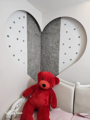 a red teddy bear sitting on a bed in front of a heart at A&K Sea View Apartament 6 in Durrës