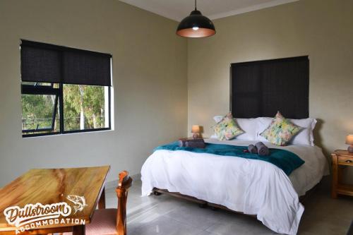 Un dormitorio con una cama y una mesa y una ventana. en Uitzicht, en Dullstroom