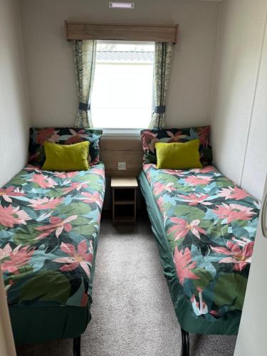 two beds in a small room with a window at Arizona - Pura Vida Holidays Caravan in Clacton-on-Sea