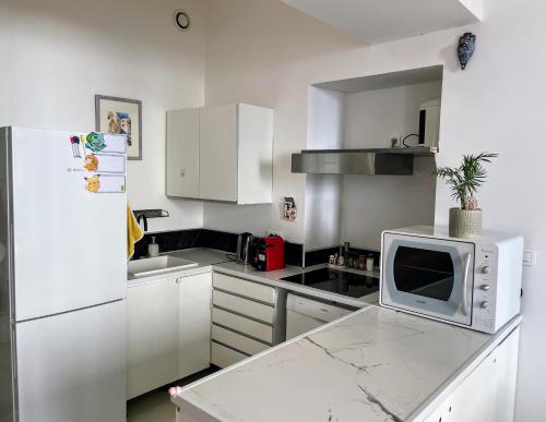 a white kitchen with a refrigerator and a microwave at Appartement Claudia - Central - Very close to Sea - Calm - AC in Nice