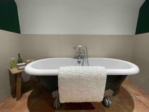 a bath tub in a bathroom with a green and white wall at Watherston Farm Cottage in Stow