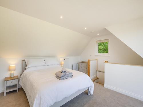 een witte slaapkamer met een bed en een raam bij South Wood Lodge in Slindon
