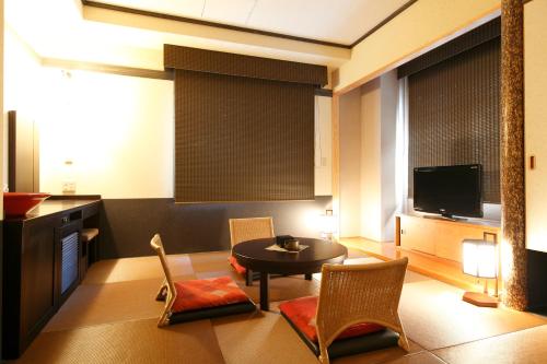 a living room with a table and chairs and a tv at Konoha in Kusatsu