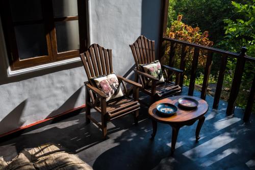 two chairs and a table on a porch at Wanakaset Forest Glamping in Kitulgala