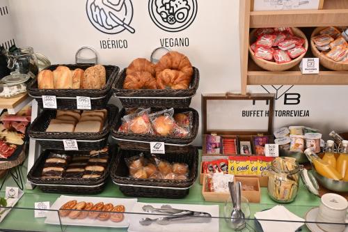 a counter with trays of bread and pastries on it at HB Torrevieja in Torrevieja