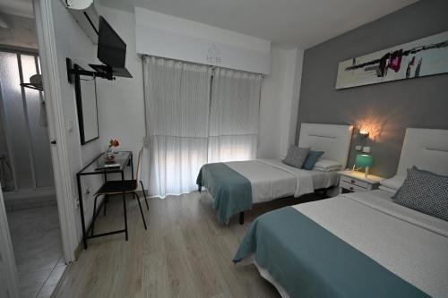 a bedroom with two beds and a desk and a television at HB Torrevieja in Torrevieja
