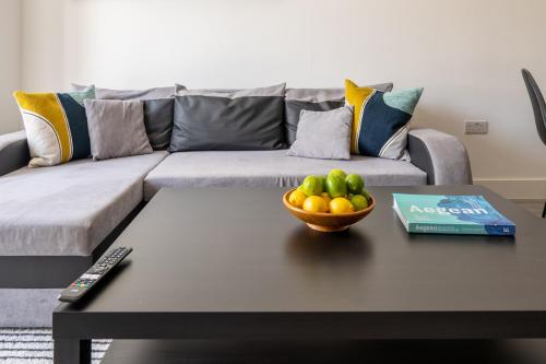 a living room with a couch and a bowl of fruit on a table at Hemel Apartments- City Zen in Hemel Hempstead