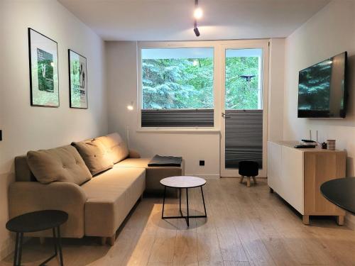 a living room with a couch and two windows at Apartament z sauną Polanica-Zdrój in Polanica-Zdrój