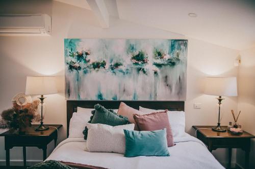 a bedroom with a bed with pillows and a painting on the wall at Araluen Boutique Accommodation in Yarra Glen