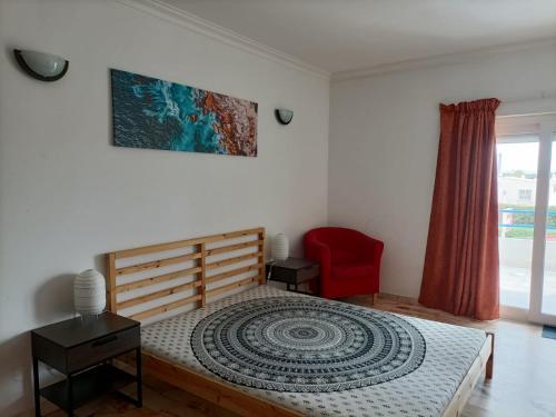een slaapkamer met een bed en een rode stoel bij Oura Li in Albufeira