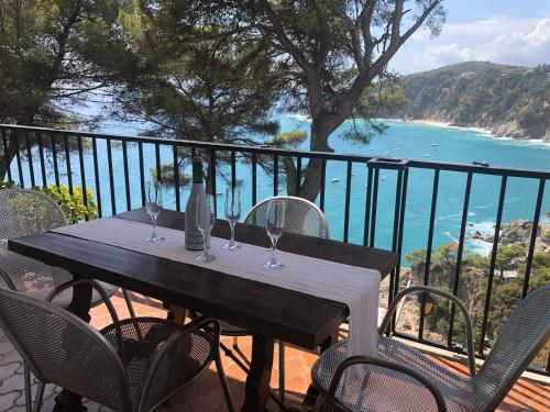 a table with wine glasses on a balcony with the ocean at LES TERRASSES de Cala Llevado in Tossa de Mar
