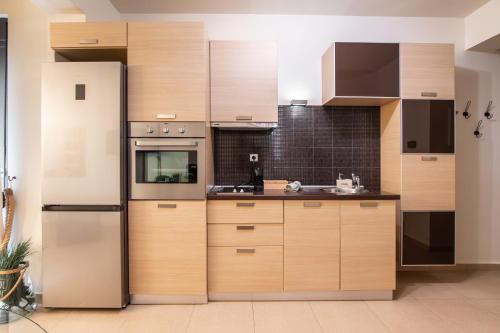 a kitchen with wooden cabinets and a refrigerator at Nefeli Residence in Alexandroupoli