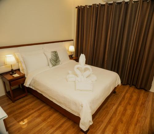a bedroom with a bed with white sheets and curtains at Amigos Dauin Hostel in Dauin