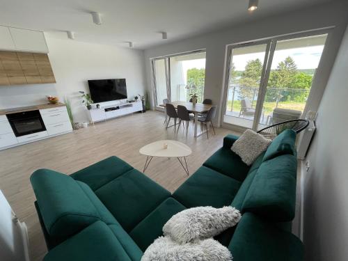 a living room with a green couch and a table at Apartament nad jeziorem Białym Augustów in Augustów