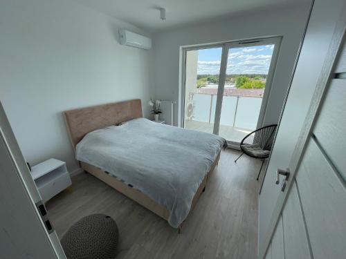 a bedroom with a bed and a large window at Apartament nad jeziorem Białym Augustów in Augustów