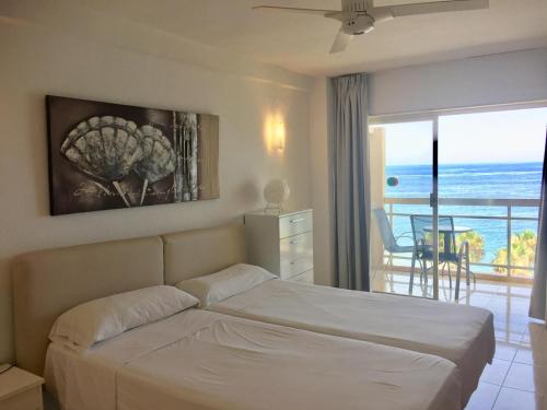 a bedroom with a bed and a view of the ocean at Apartamentos Apal Chinasol in Almuñécar