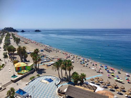 a beach with a lot of umbrellas and crowds of people at Apartamentos Apal Chinasol in Almuñécar