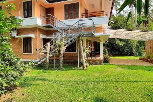 a house with a staircase in front of a yard at Joan's Homestay Near Kumarakom in Vaikom