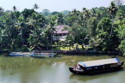 a boat in the water next to a house at Joan's Homestay Near Kumarakom in Vaikom