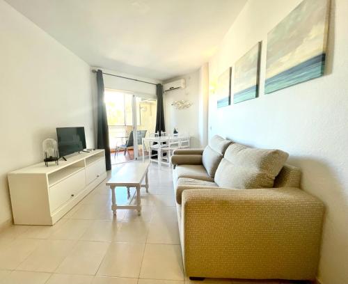 a living room with a couch and a tv and a table at Apartamentos Apal Chinasol in Almuñécar