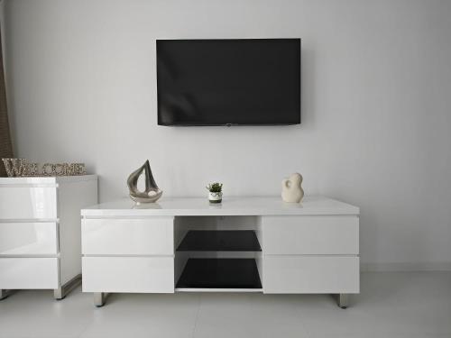a white dresser with a television on a wall at Oxygen Neptun by BOUTIQUE 23 in Jupiter